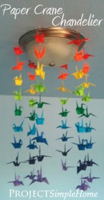 Rainbow paper cranes hanging around a ceiling light